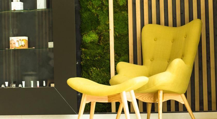 Zonă de relaxare din Forest Spa, cu fotoliu galben în fața peretelui din mușchi stabilizat